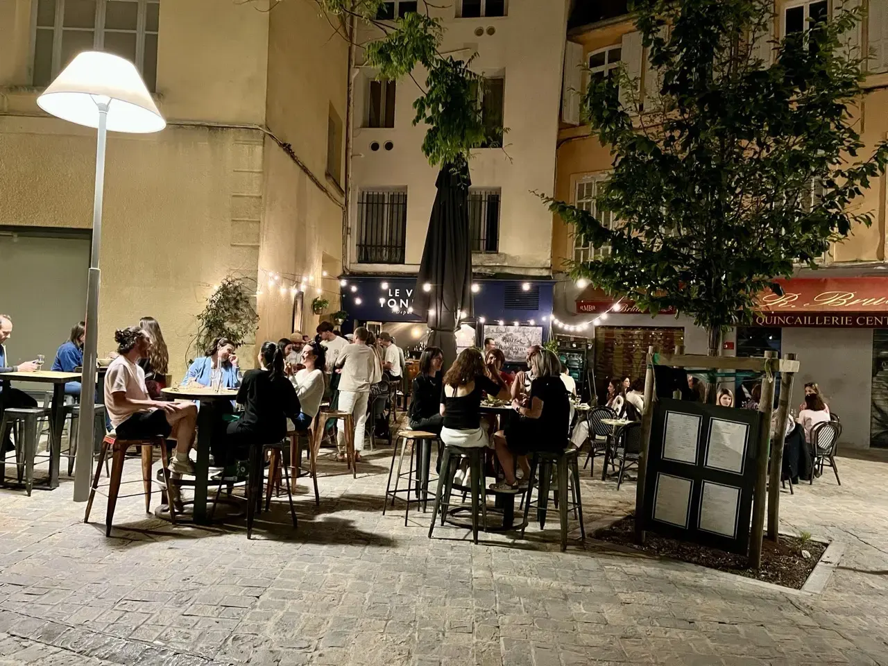 La terrasse du Vieux Tonneau animée le soir, sous l’arbre et les guirlandes.